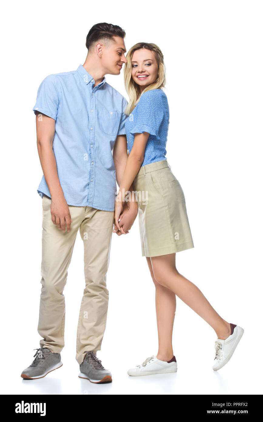 Lächelndes Paar in blauen Shirts halten sich an den Händen isoliert auf weißem Stockfoto