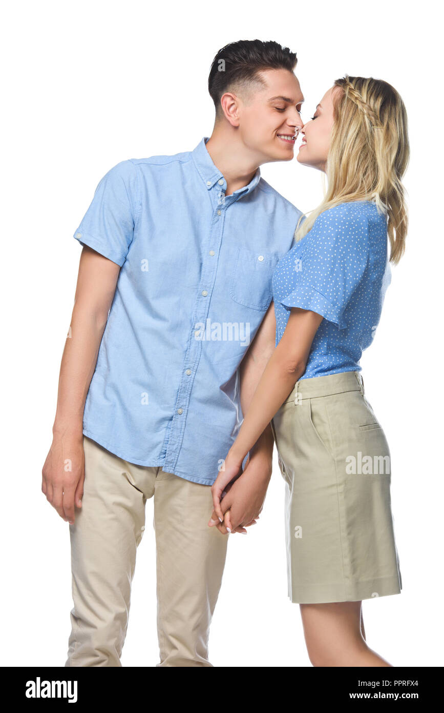 Lächelndes Paar in blauen Shirts isoliert auf weißem küssen Stockfoto