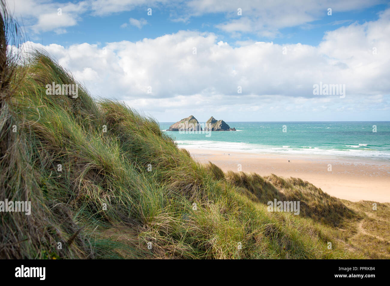 Möwe oder Carters von Felsen, Holywell Bay in der Nähe von Newquay, Cornwall. Küstenlandschaft mit Gras bedeckte Dünen, felsigen kleinen Inseln und blauen bewölkten Himmel Hintergrund. Stockfoto