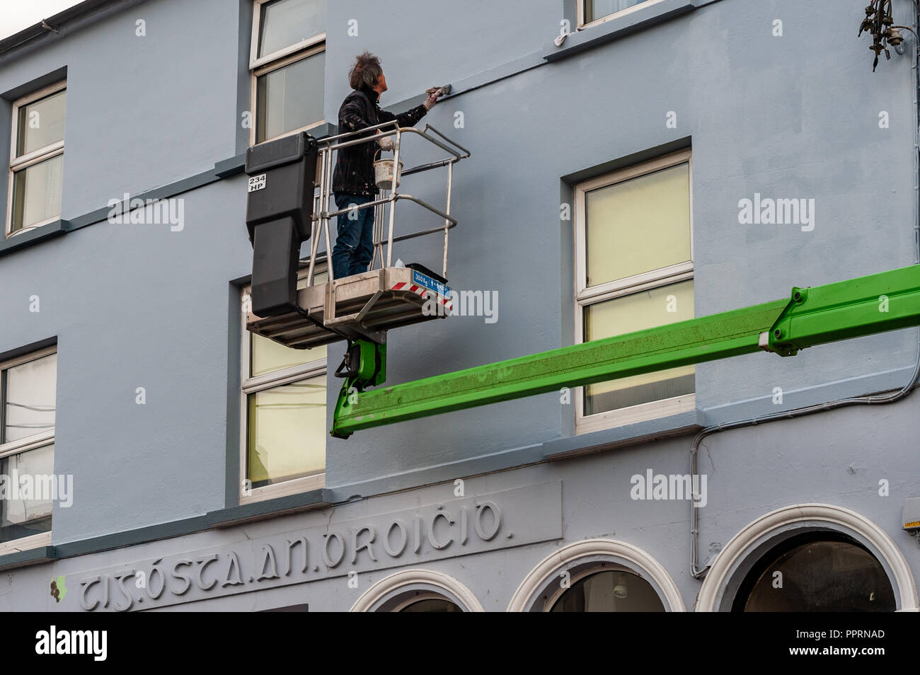 Maler und Dekorateur auf einer erhöhten Plattform Malerei ein Gebäude in Bantry, West Cork, Irland. Stockfoto