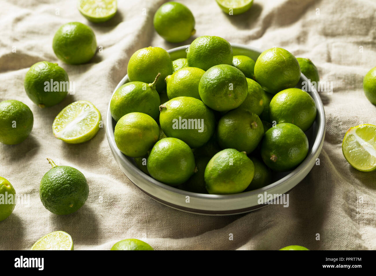 Rohe grüne Bio Key Limes in eine Schüssel geben Stockfoto