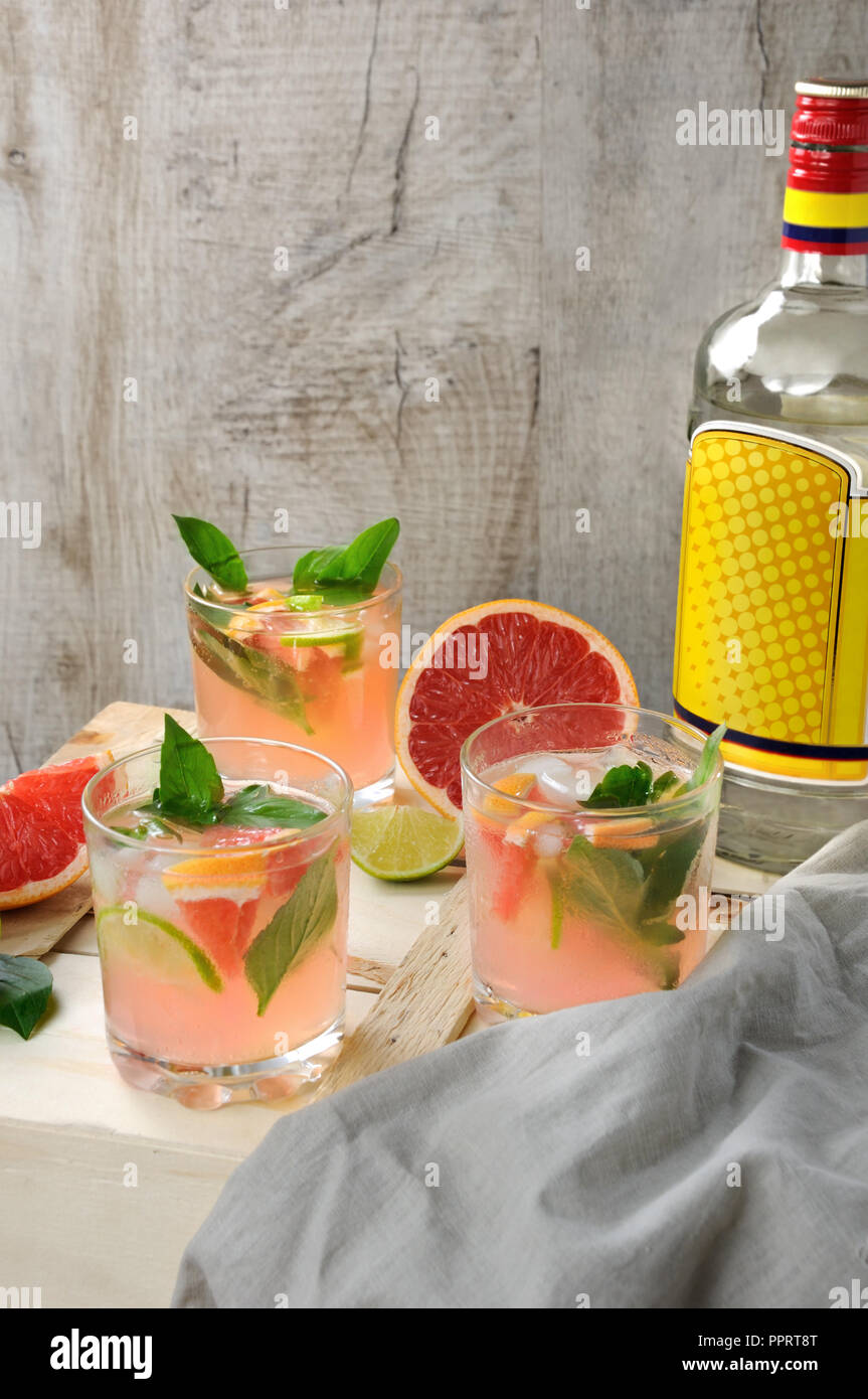 Cocktail von London Dry Gin mit Saft aus gepressten roten Grapefruit und Blätter von empfindlichen Basilikum Zitrone, Limette Schichten und gekühlte Eiswürfel. Stockfoto