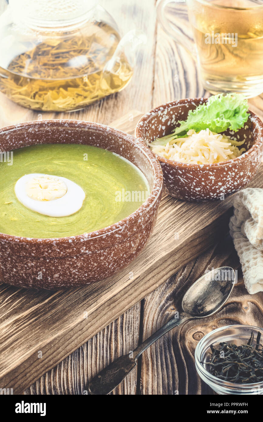 Püree Cremesuppe von grünem Salat, Spinat und Käse in der Schüssel dekoriert Stück gekochtes Ei an Bord für Gerichte auf den Tisch, serviert mit Stockfoto