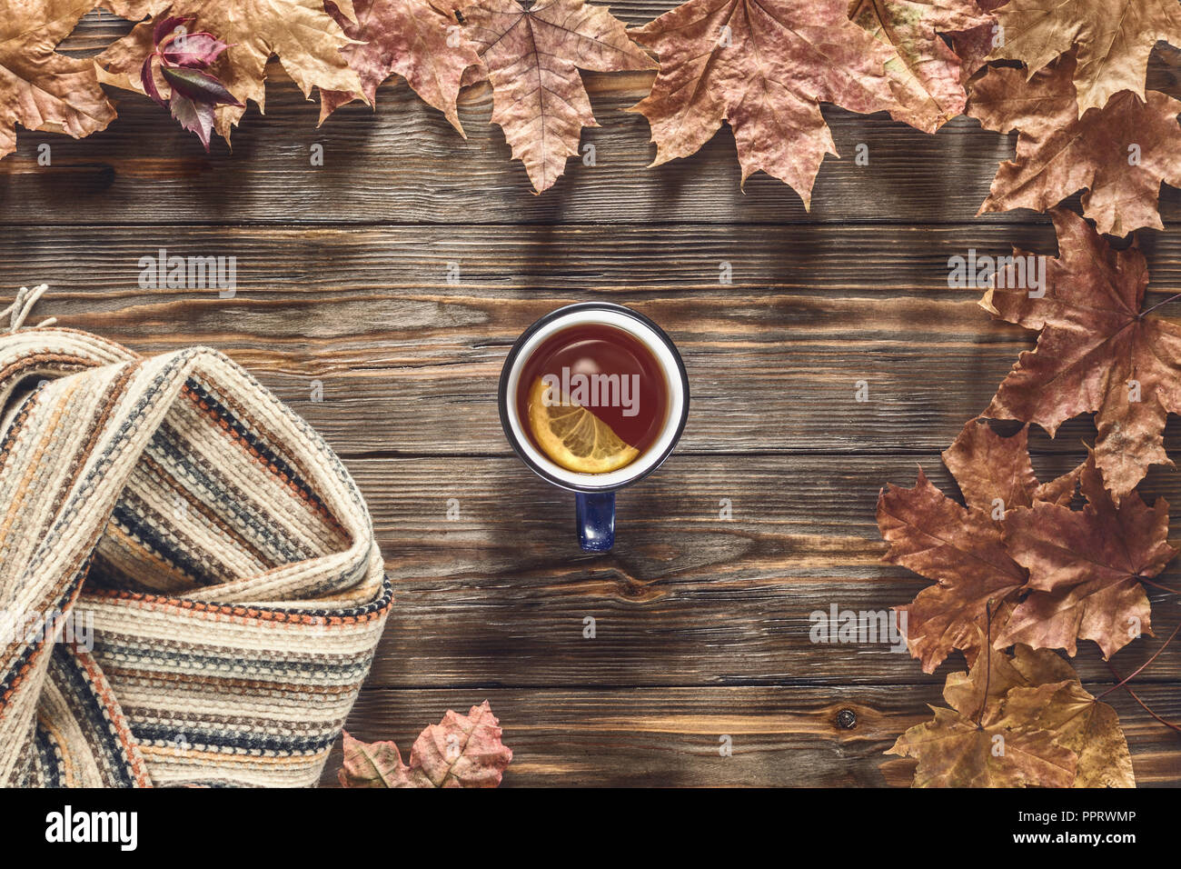 Herbst Mode saisonale Konzept skandinavischen Strickschal Tasse heißer schwarzer Tee Kaffee Fallen gefallen Ahornblätter auf Holztisch mit Notebook pen Flachbild la Stockfoto