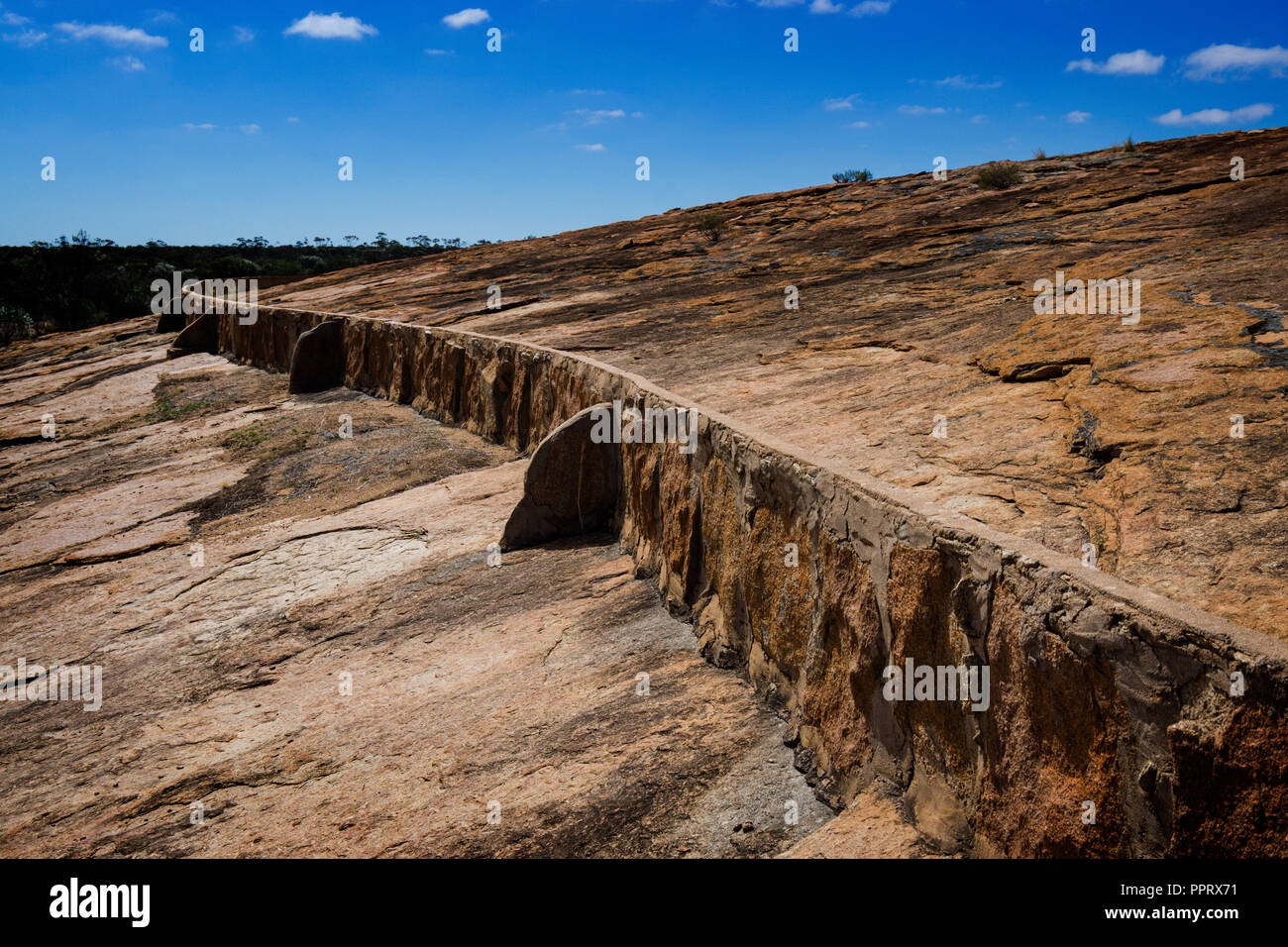 Niedrige Steinmauer leitet Stichwahl regen Wasser in Wassereinzugsgebieten Tank bei Beringbooding Rock Western Australia Stockfoto