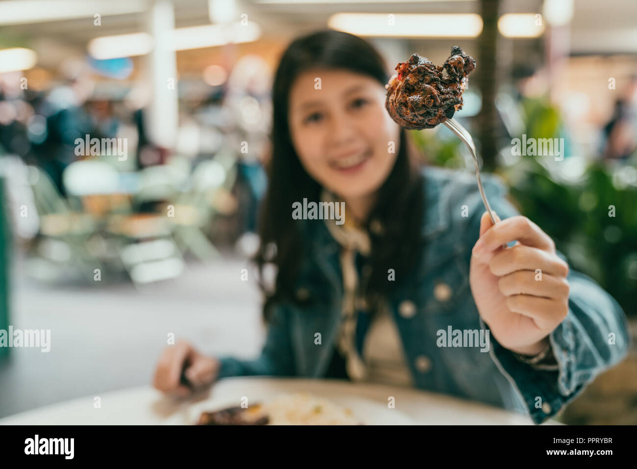 Hübsche Frau mit Gabel ihr leckeres Essen zu zeigen, sie gibt die Kamera ein grosses attraktives Lächeln Stockfoto