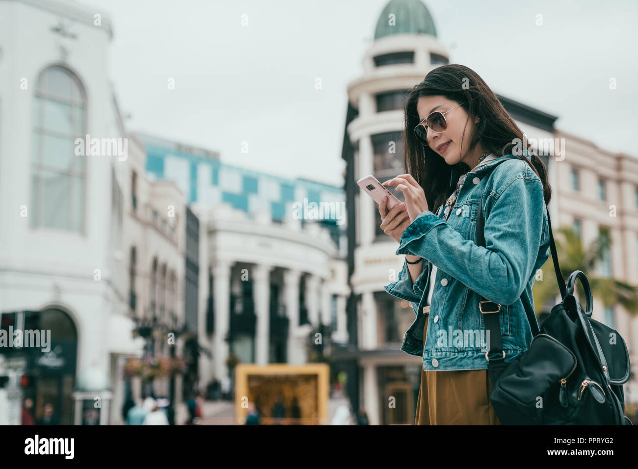 Schöne Frau mit Smartphone die Lage Ihrer bevorzugten Tasche Shop zu suchen Stockfoto