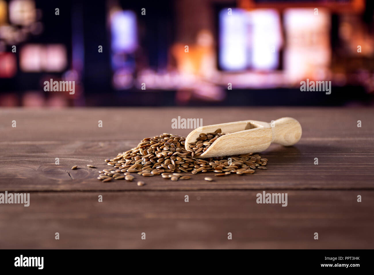 Viele von ganzen frischen braunen Leinsamen mit Holz- Schaufel mit Restaurant im Hintergrund Stockfoto