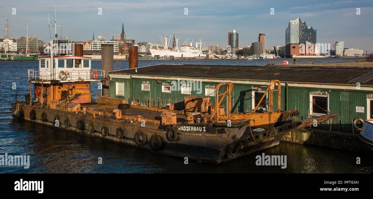 Hamburger Hafen, Arbeitsschiff WASSERBAU ICH vor Holzbaracke, am Horizont die Skyline der Stadt mit Museumsschiff CAP SAN DIEGO und Elbphilharmonie Stockfoto