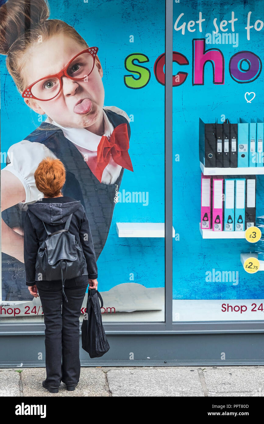 Eine Frau mit roten Haaren zu großen Poster im Fenster eines Shop in Truro in Cornwall. Stockfoto