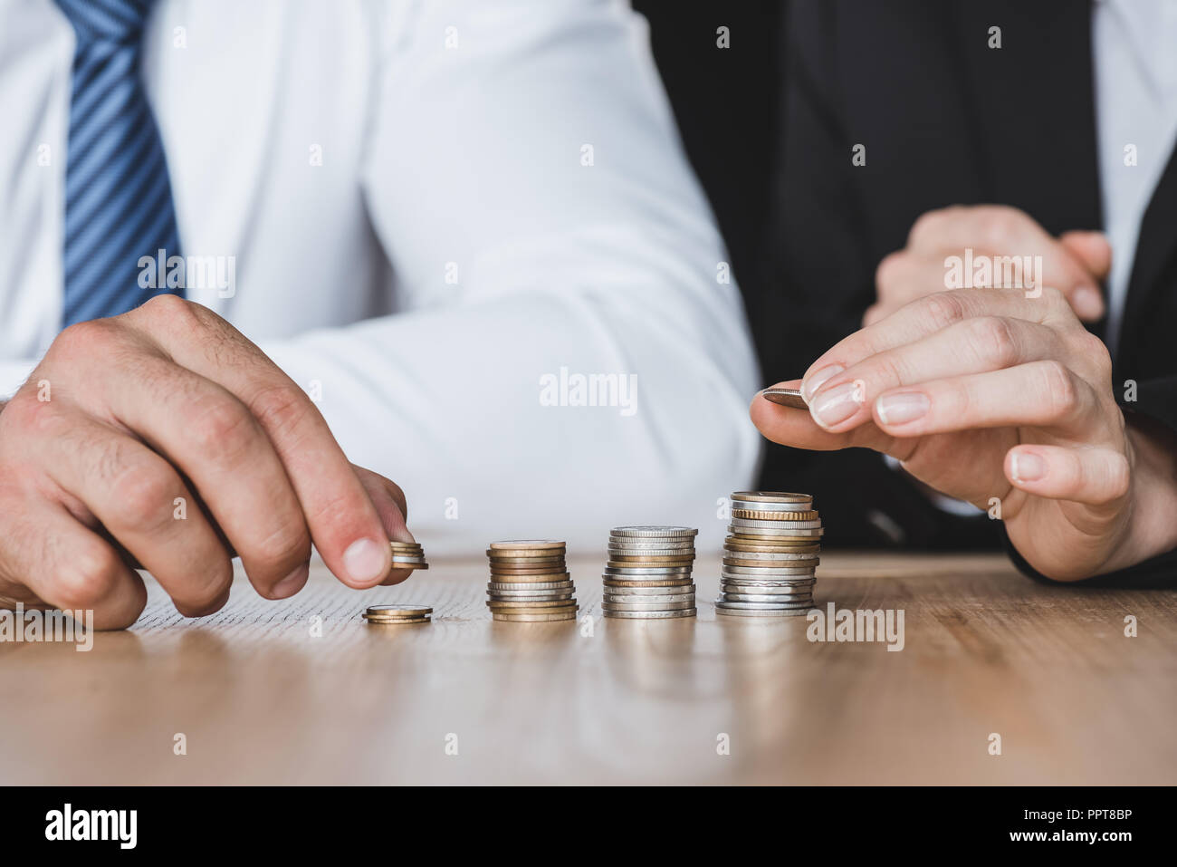 Zugeschnittenes Bild der Finanziers stapeln Münzen auf den Tisch im Büro Stockfoto