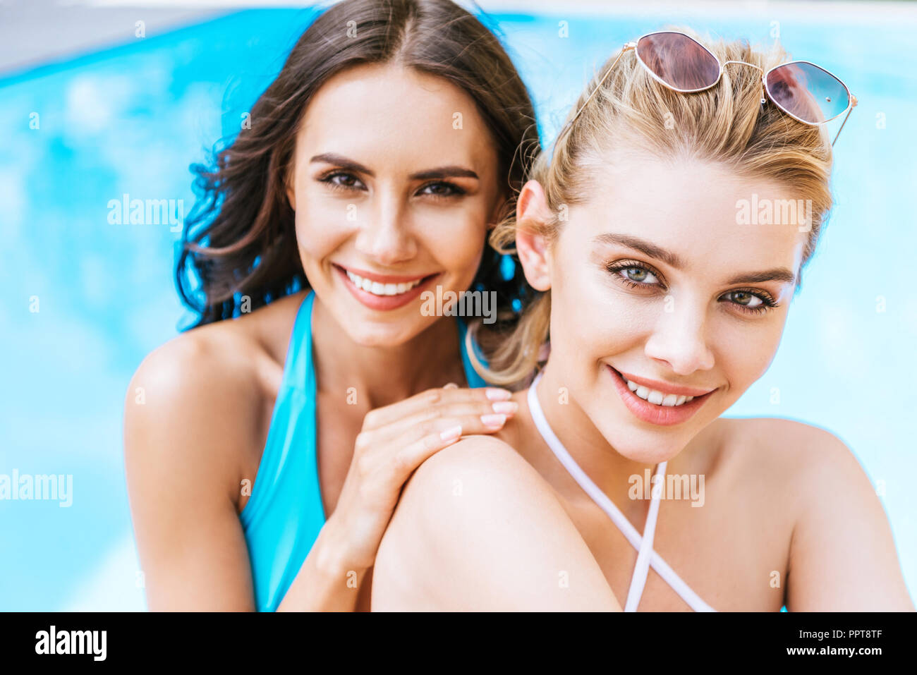 Schöne glückliche junge Freundinnen Lächeln auf die Kamera in der Nähe von Schwimmbad Stockfoto