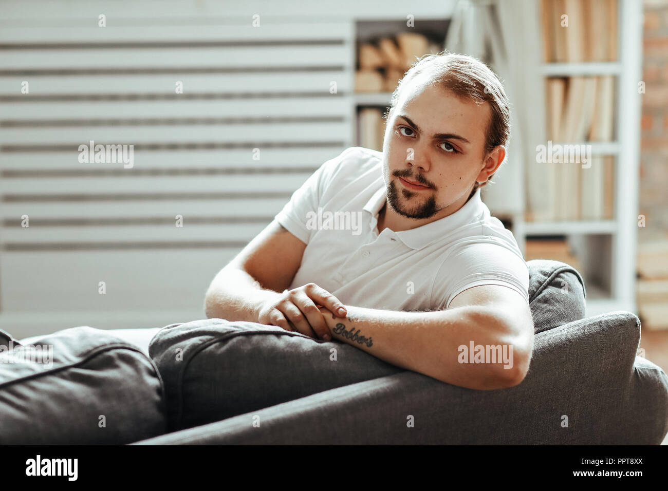 Schöner Mann sitzt auf dem Sofa zu Hause Stockfoto