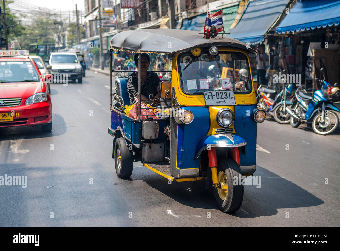 Tuctuc, einem DreirädrigenZyklus, mit einem weiblichen Passagier durch die Straßen von Bangkok