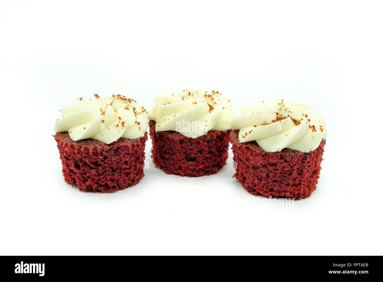 Drei schöne Red velvet Cupcakes in einer Reihe auf einem weißen Hintergrund. Die Kuchen an beiden Enden sind im Fokus gowing weicher nach hinten. Gutes image für Ba Stockfoto