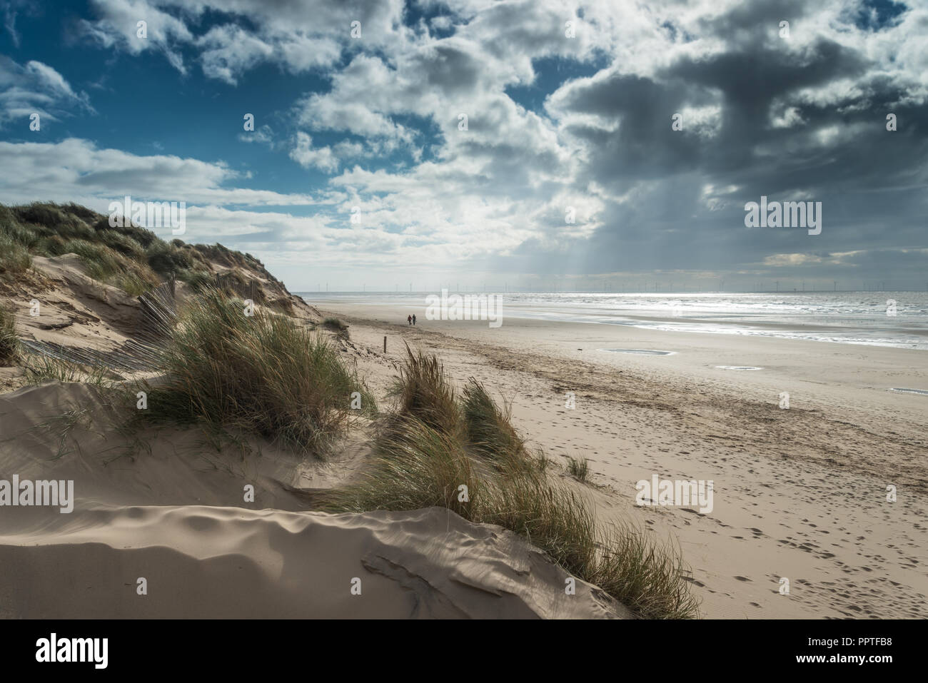 Der Sandstrand von Formby mit Sanddünen auf einem sonnigen September Nachmittag im Herbst, Merseyside, England, Großbritannien mit zwei Menschen zu Fuß in der Ferne. Stockfoto