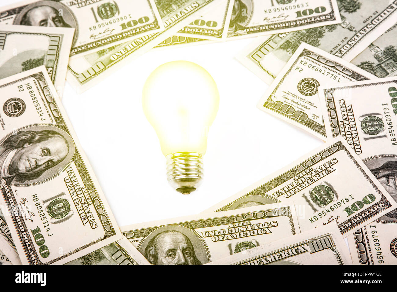 Stapel von Dollar Banknoten mit Glühbirne auf weißem Hintergrund. Stockfoto