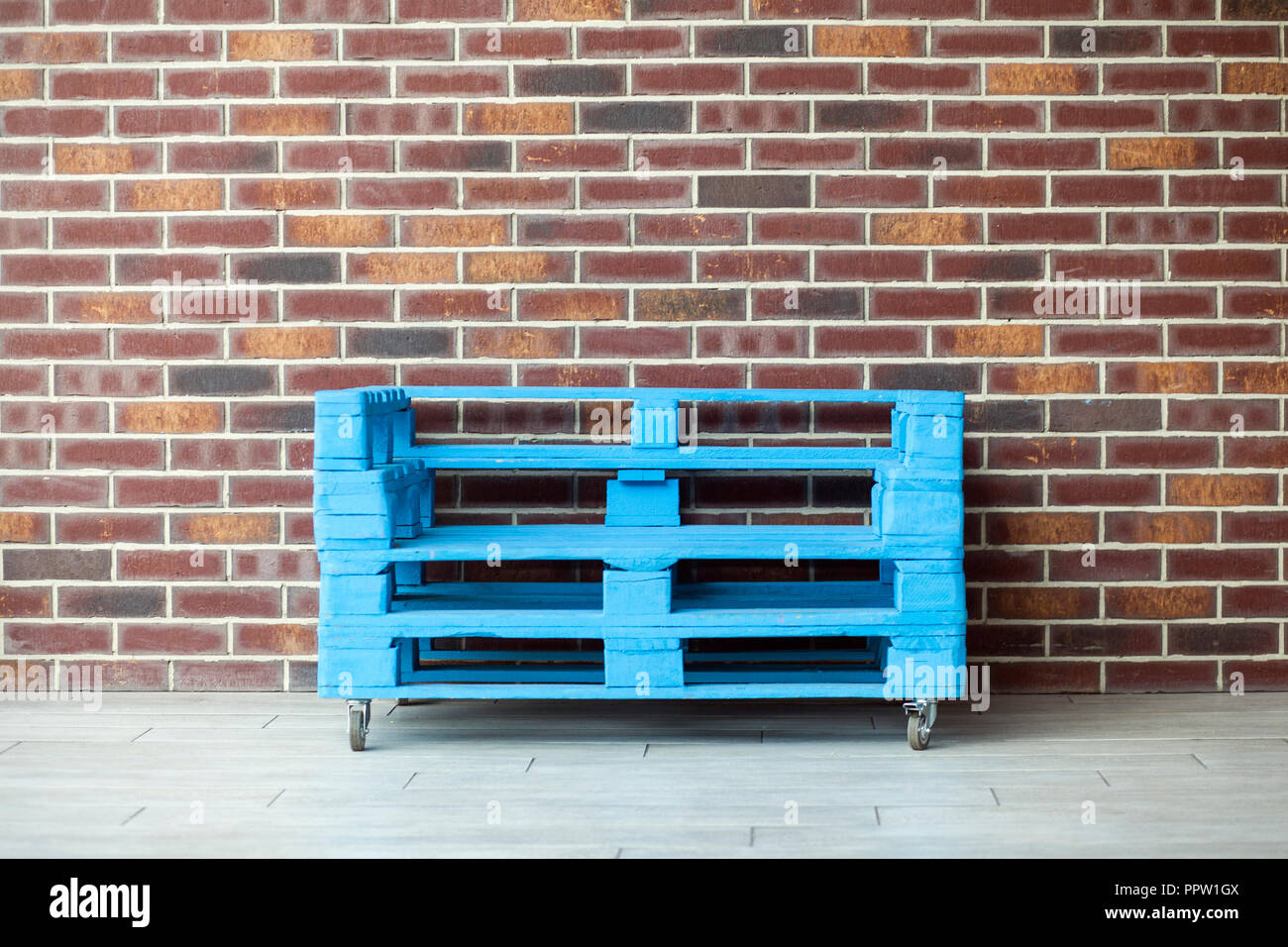 Blau Versand Paletten für das Sitzen mit Rädern auf Mauer Hintergrund. Stockfoto