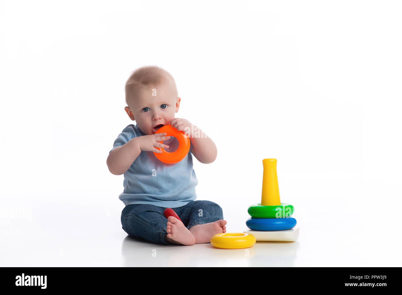 Ein sieben Monate altes Baby Junge spielt mit einem Ring Spielzeug stapeln. Im Studio auf einem weißen, nahtlose Kulisse erschossen. Stockfoto