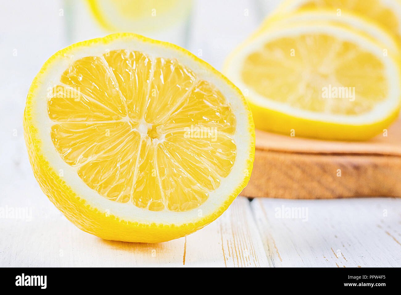 Ein Becherglas und einen Krug kalten Limonade auf einem weißen Hintergrund Holz umgeben von Zitronen Stockfoto