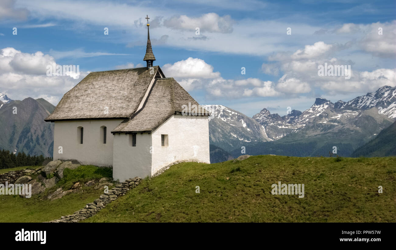 In der Nähe des Dorfes Bettmeralp im Wallis (Schweiz) eine kleine weiße Kirche in den grünen Feldern steht. Stockfoto