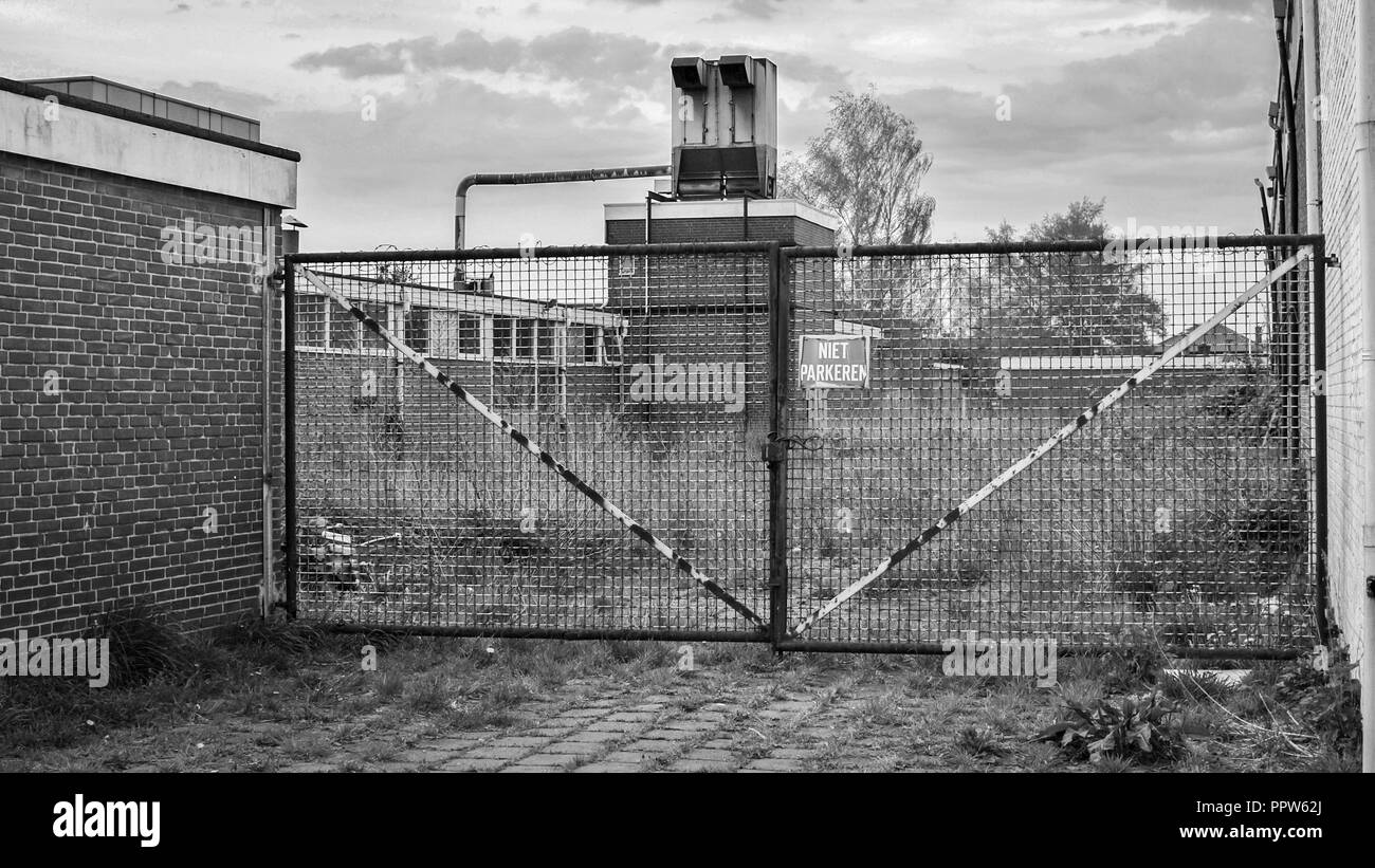 Auf einem verlassenen Industriegelände einen großen eisernen Tor gegen ein geschlossenes Werk gesperrt ist. Es ist in der Stadt von Almelo in der Provinz Overijssel Stockfoto