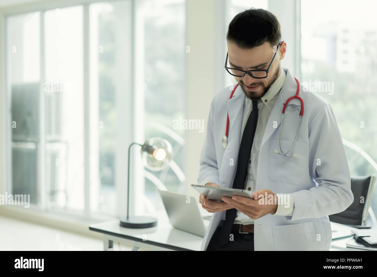 Arzt im Krankenhaus arbeiten mit moderner Technologie für gesund. Freundliche mann Arzt schauen und lächeln für gutes Ergebnis von Patientendaten. Stockfoto
