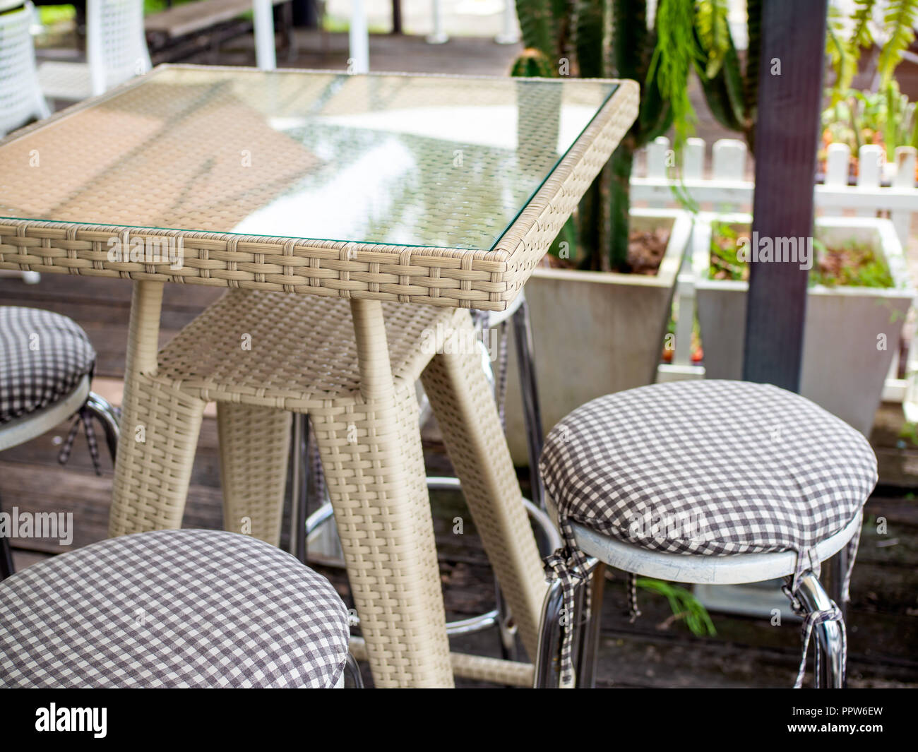 Close up moderne Webart rattan Tisch mit Glas und Edelstahl Stühle mit  Kissen auf Holzboden. Gemischt und Retro Cafe übereinstimmen  Stockfotografie - Alamy