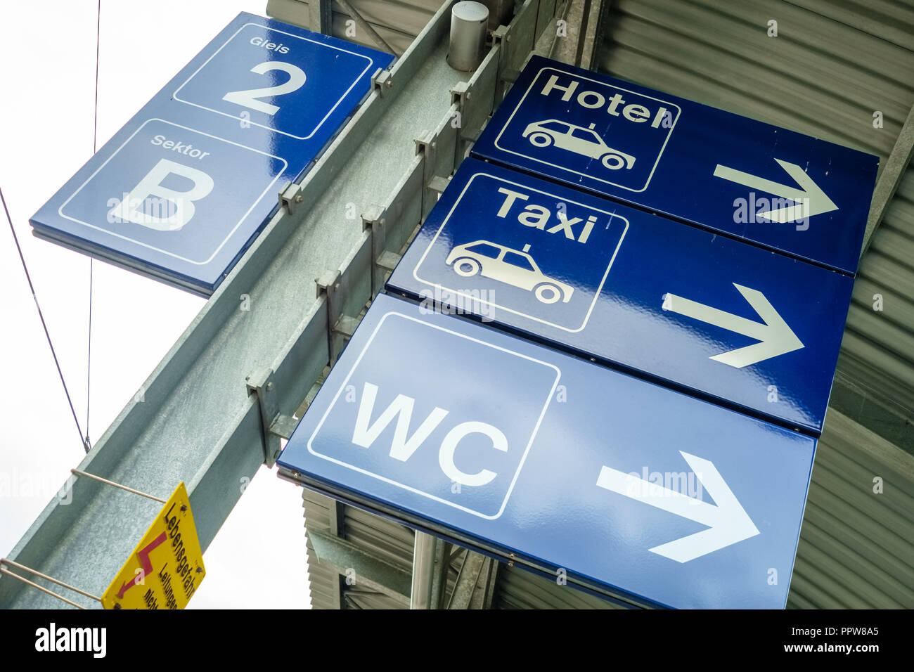 Ein blaues Schild zeigt an, wo das Bad am Bahnhof der Schweizer Dorf Wengen (Berner Oberland) und das Hotel und die Taxis sind lo Stockfoto