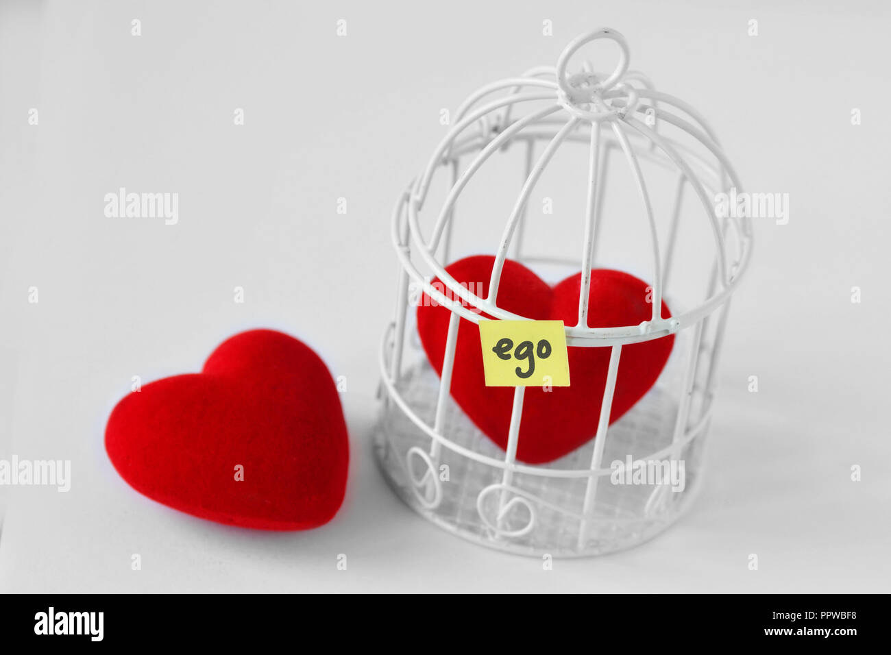 Sie Herz und Herz in einem Vogelkäfig mit dem Wort Ego auf Papier Hinweis geschrieben - Liebe und Freiheit Konzept Stockfoto