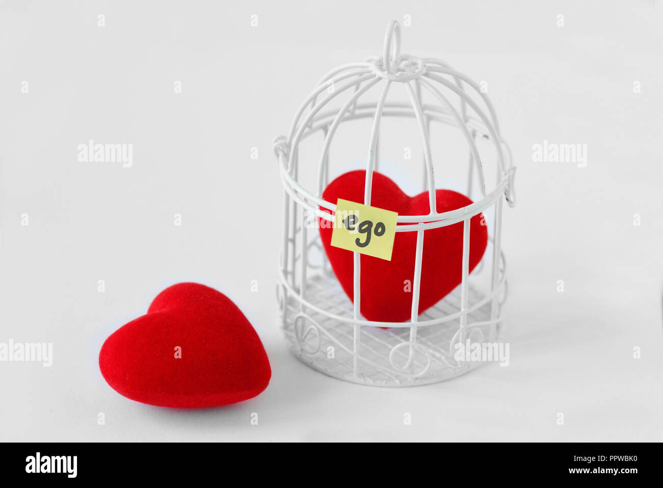 Sie Herz und Herz in einem Vogelkäfig mit dem Wort Ego auf Papier Hinweis geschrieben - Liebe und Freiheit Konzept Stockfoto