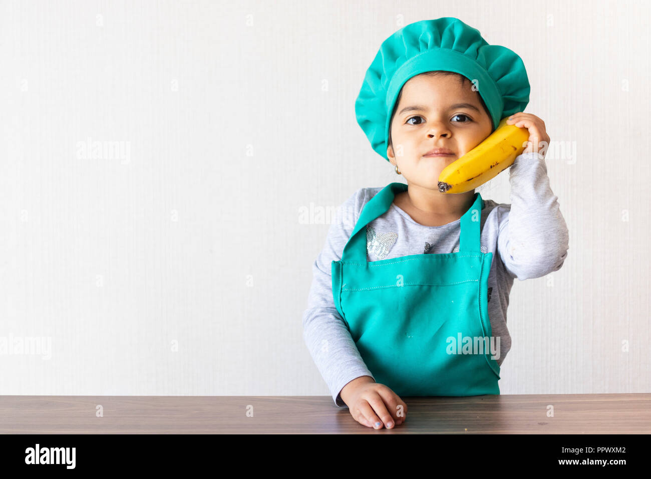 Süße kleine Mädchen Kochen, Spielen mit einer Banane, als ob es sich um ein Telefon Stockfoto