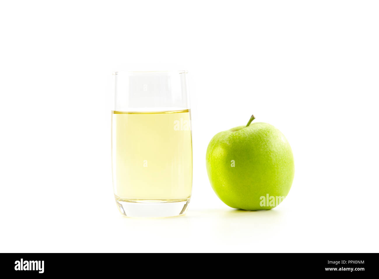 Ein grüner Apfel und ein Glas Apfelsaft auf weißem Hintergrund. Stockfoto