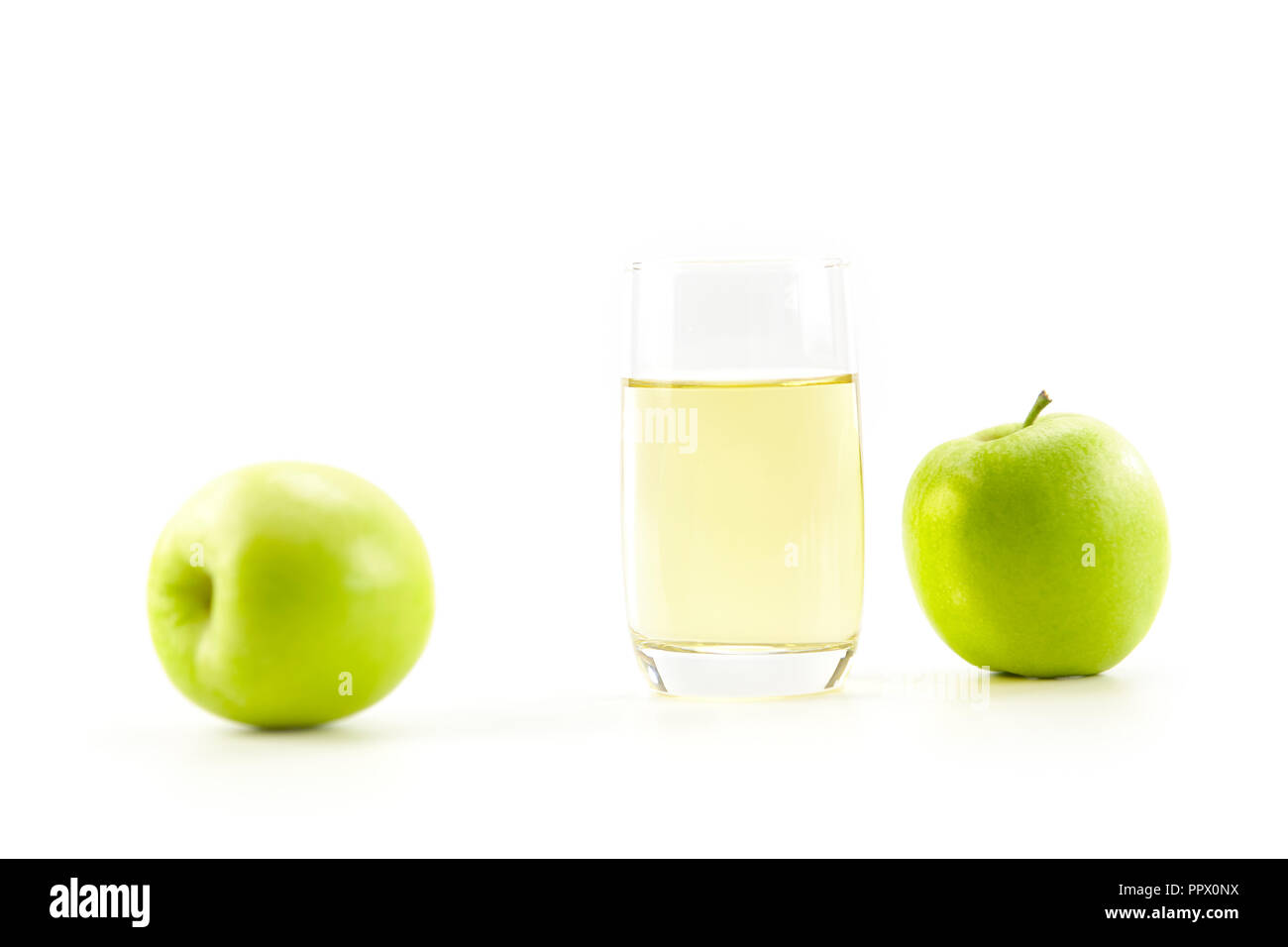 Zwei grüne Äpfel und ein Glas Apfelsaft auf weißem Hintergrund. Stockfoto