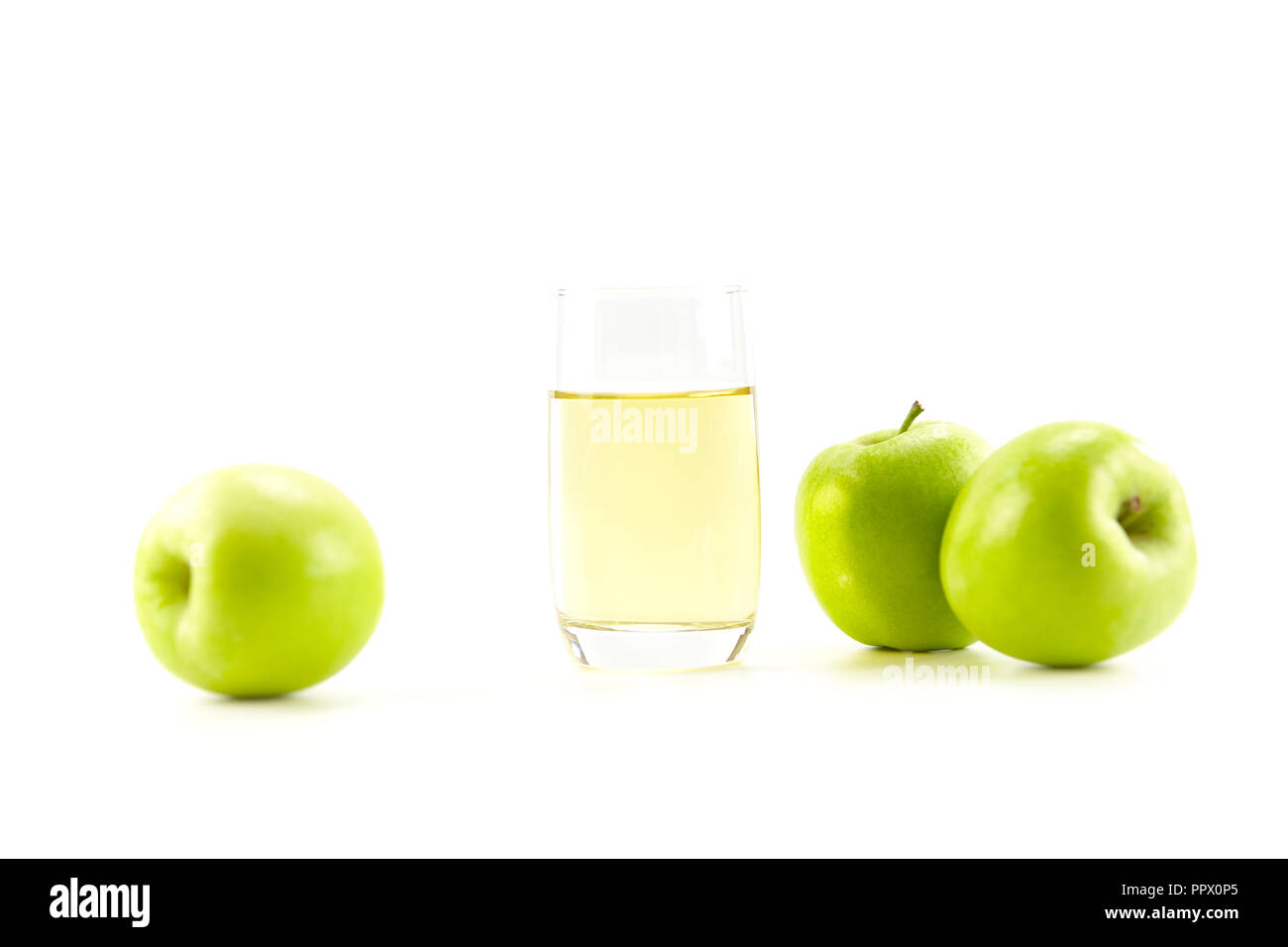 Drei grüne Äpfel und ein Glas Apfelsaft auf weißem Hintergrund. Stockfoto