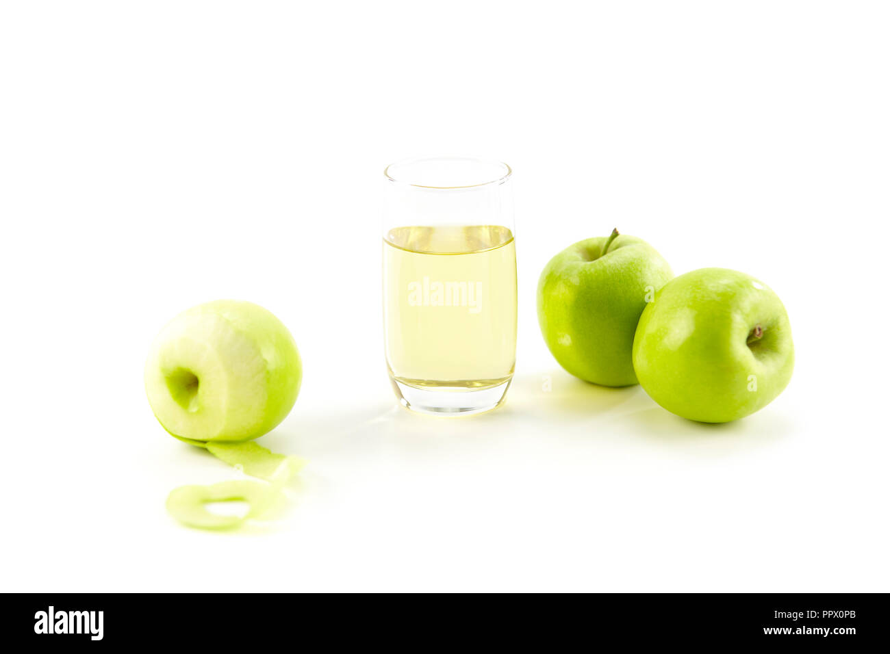 Drei grüne Äpfel und ein Glas Apfelsaft auf weißem Hintergrund. Stockfoto