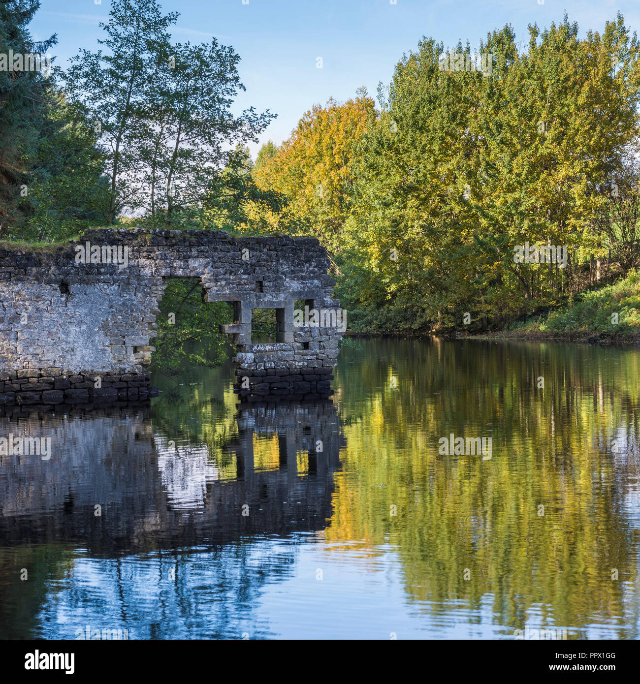 Malerischer Blick auf Thruscross Behälter mit zerbröckelnden Mauer von Flachs Mill Ruinen im Wasser spiegelt - Washburn Tal, North Yorkshire, England, UK. Stockfoto