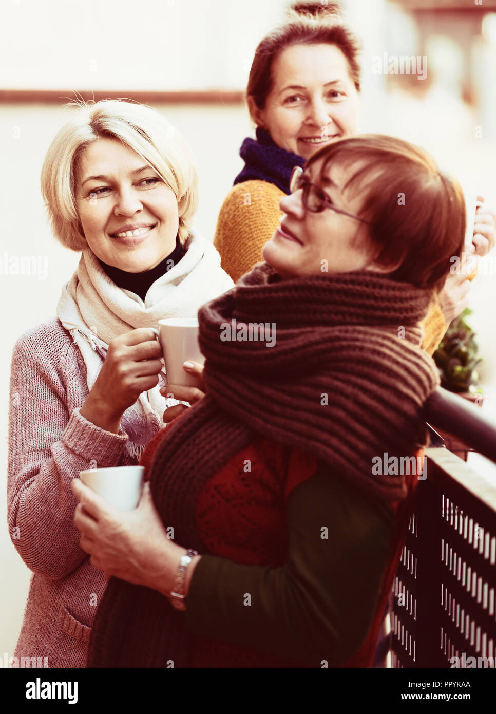 Zwei reife Frauen trinken einen Kaffee auf dem Balkon und lächelnd Stockfoto