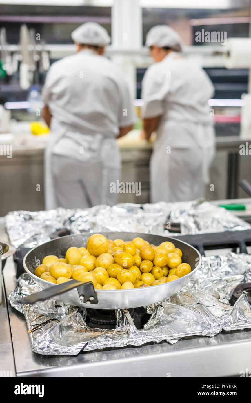 Kleine Kartoffeln auf Silber pan mit zwei Küche Arbeiter mit Schürzen als Hintergrund Stockfoto