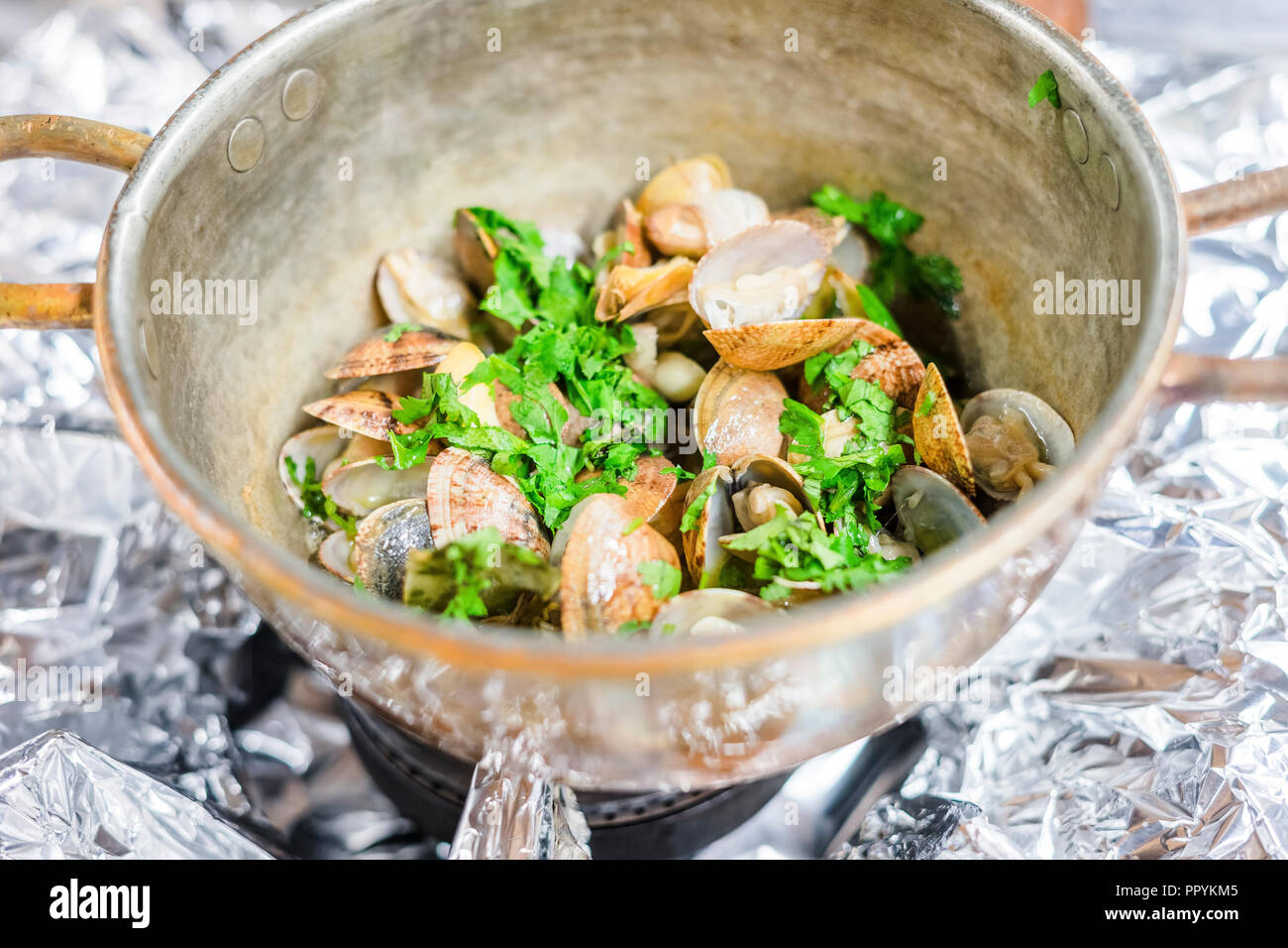 Muscheln mit Knoblauch und Koriander in einem Kupfer, Bronze pot Stockfoto