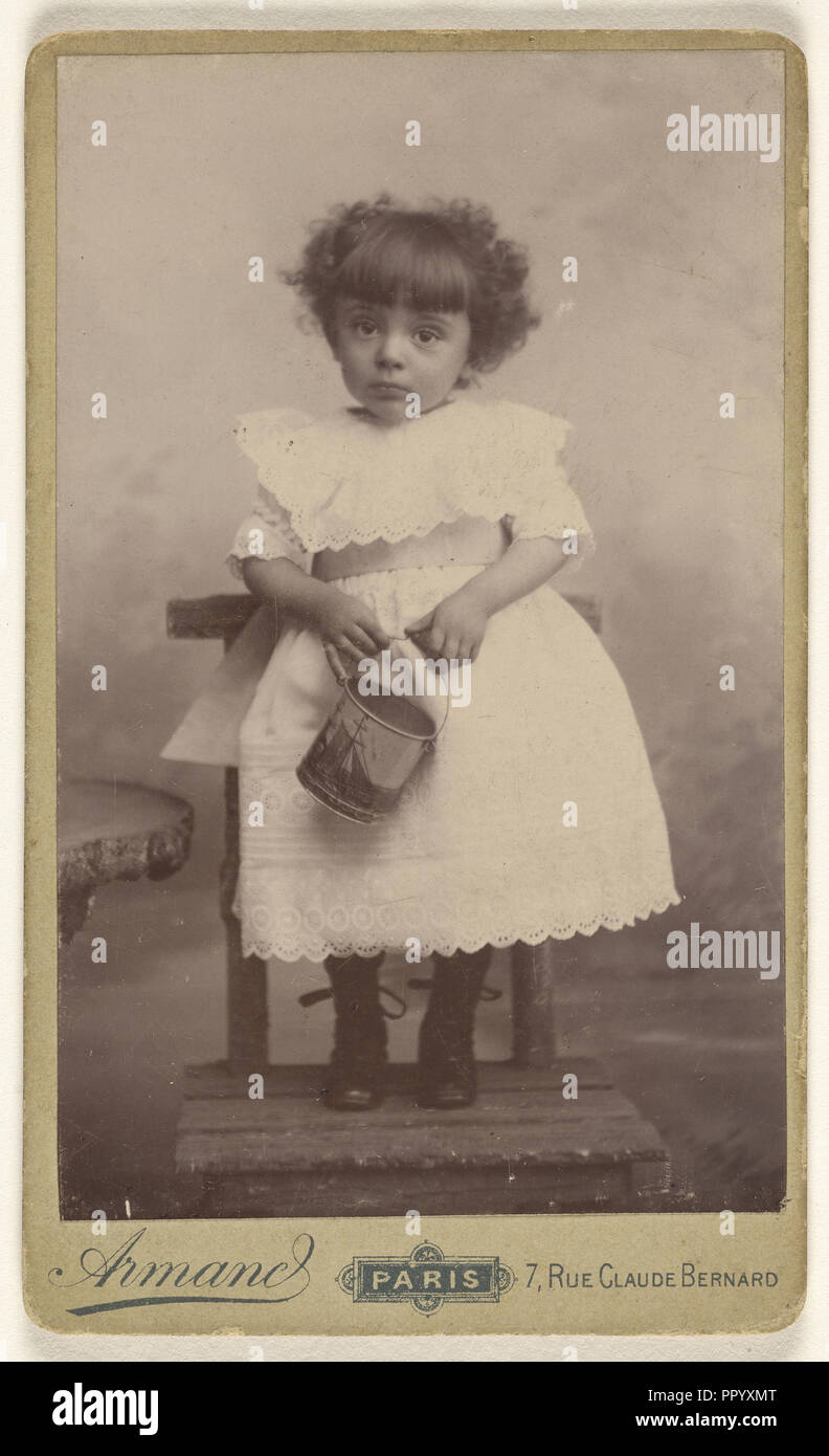 Kleines Mädchen stehend auf einem Stuhl, halten Sie einen Eimer mit einem Schiff auf ihm; Armand; 1885 - 1895; Silbergelatineabzug Stockfoto