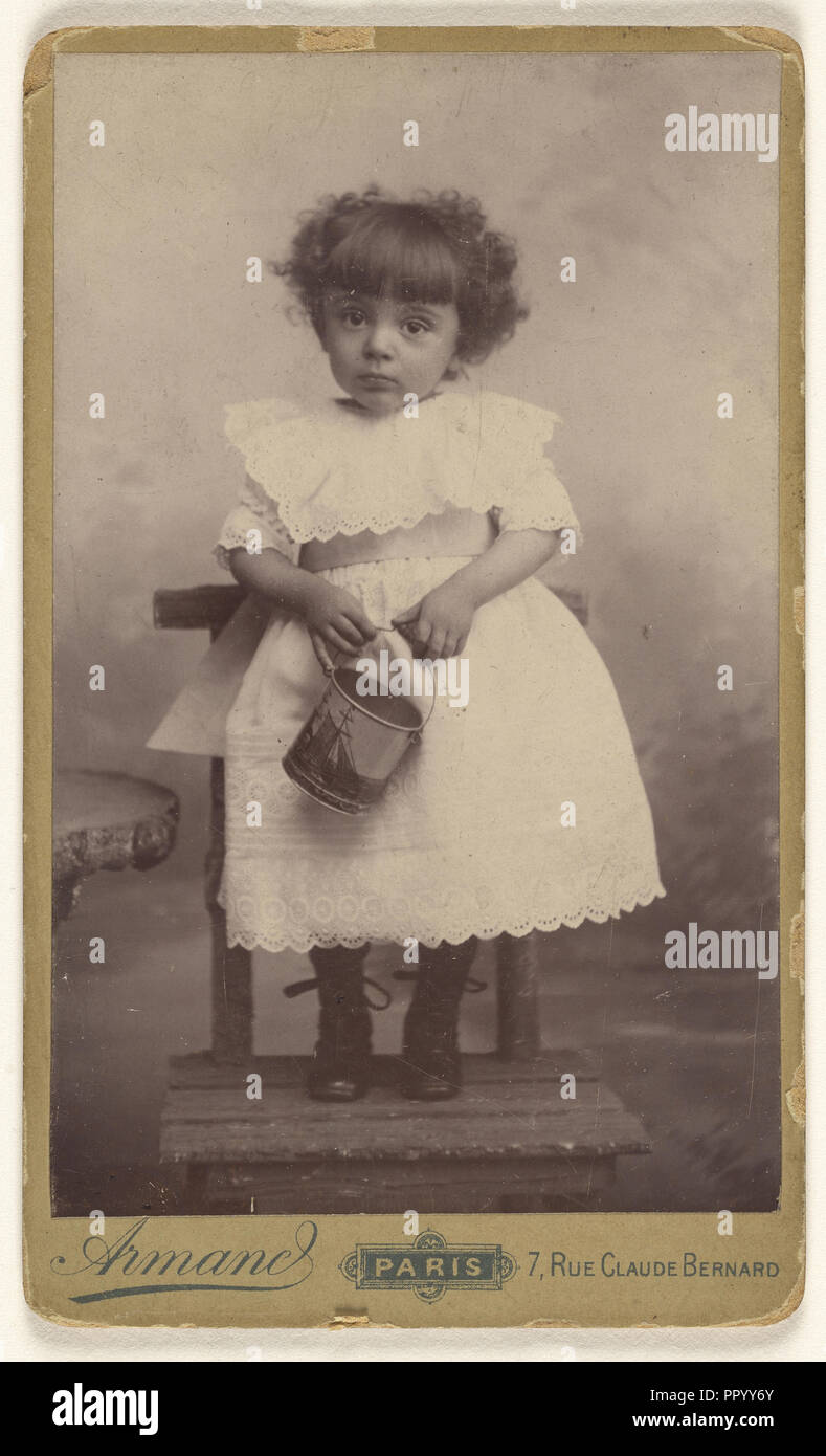 Kleines Mädchen stehend auf einem Stuhl, halten Sie einen Eimer mit einem Schiff auf ihm; Armand; 1880 - 1890; Silbergelatineabzug Stockfoto
