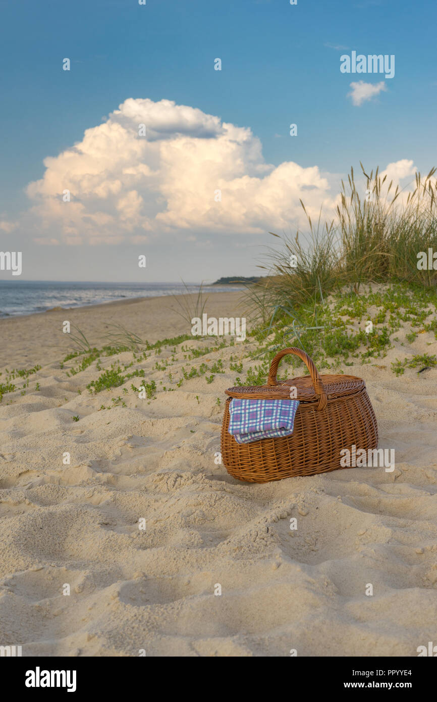 Picknickkorb gegen malerischen Strand und Wolken, Wochenende Konzept Stockfoto