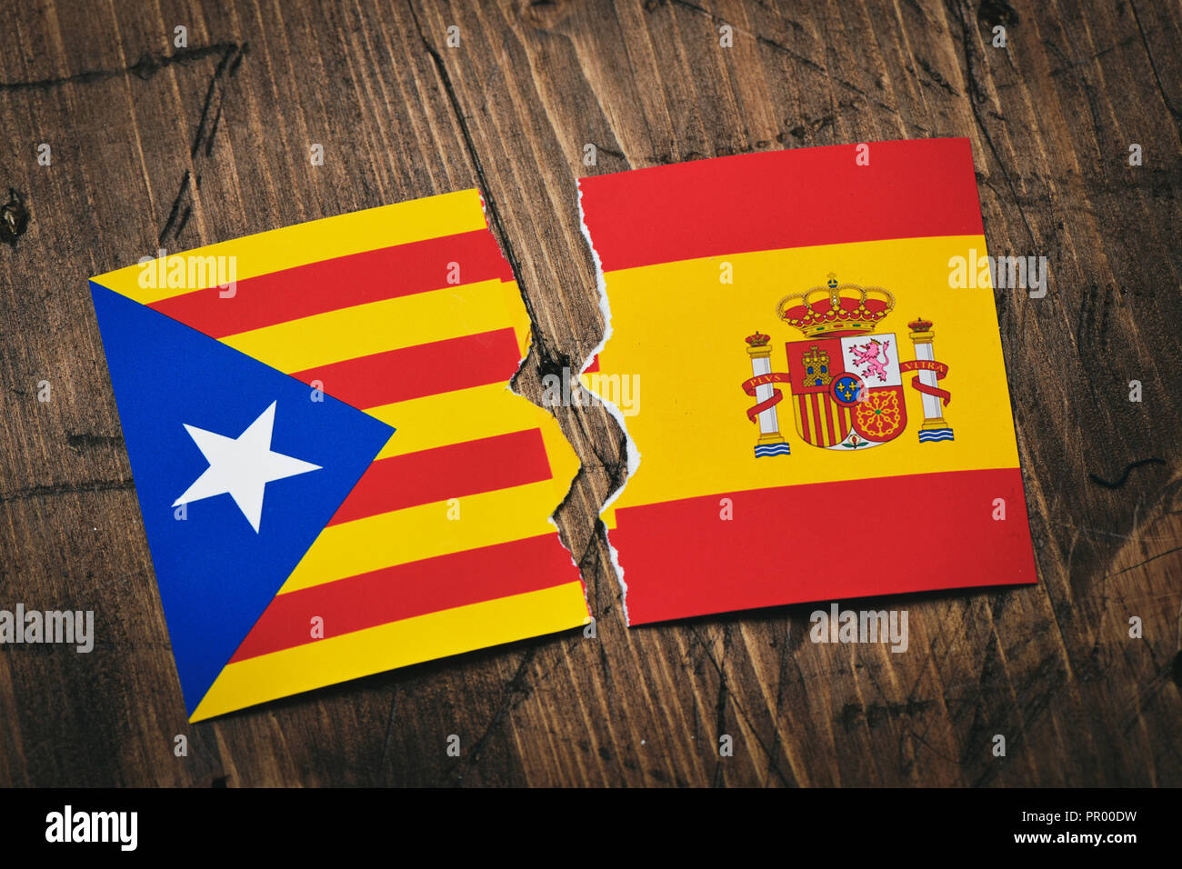 Die Estelada, die katalanische Flagge, die Unabhängigkeit und die Flagge von Spanien, auf einem rustikalen Holzmöbeln Oberfläche gebrochen Stockfoto