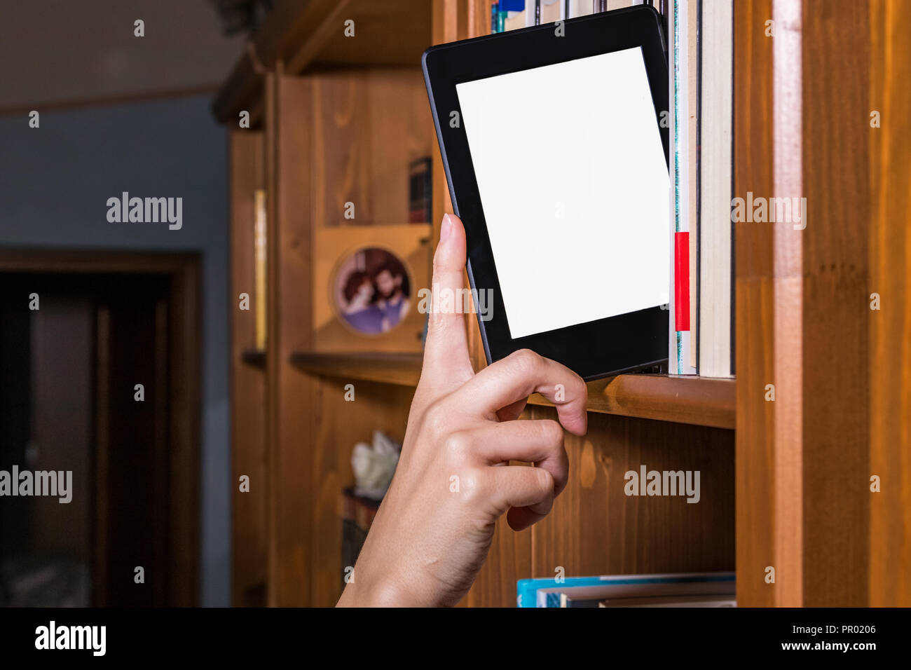 Frau hand Auswahl e Reader unter Bücher auf einem Bücherregal Stockfoto