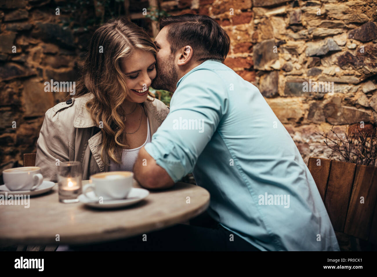 Lächelndes Paar im Coffeeshop Zeit miteinander zu verbringen. Man Flüstern in den Ohren seiner Freundin in einem Restaurant sitzen. Stockfoto