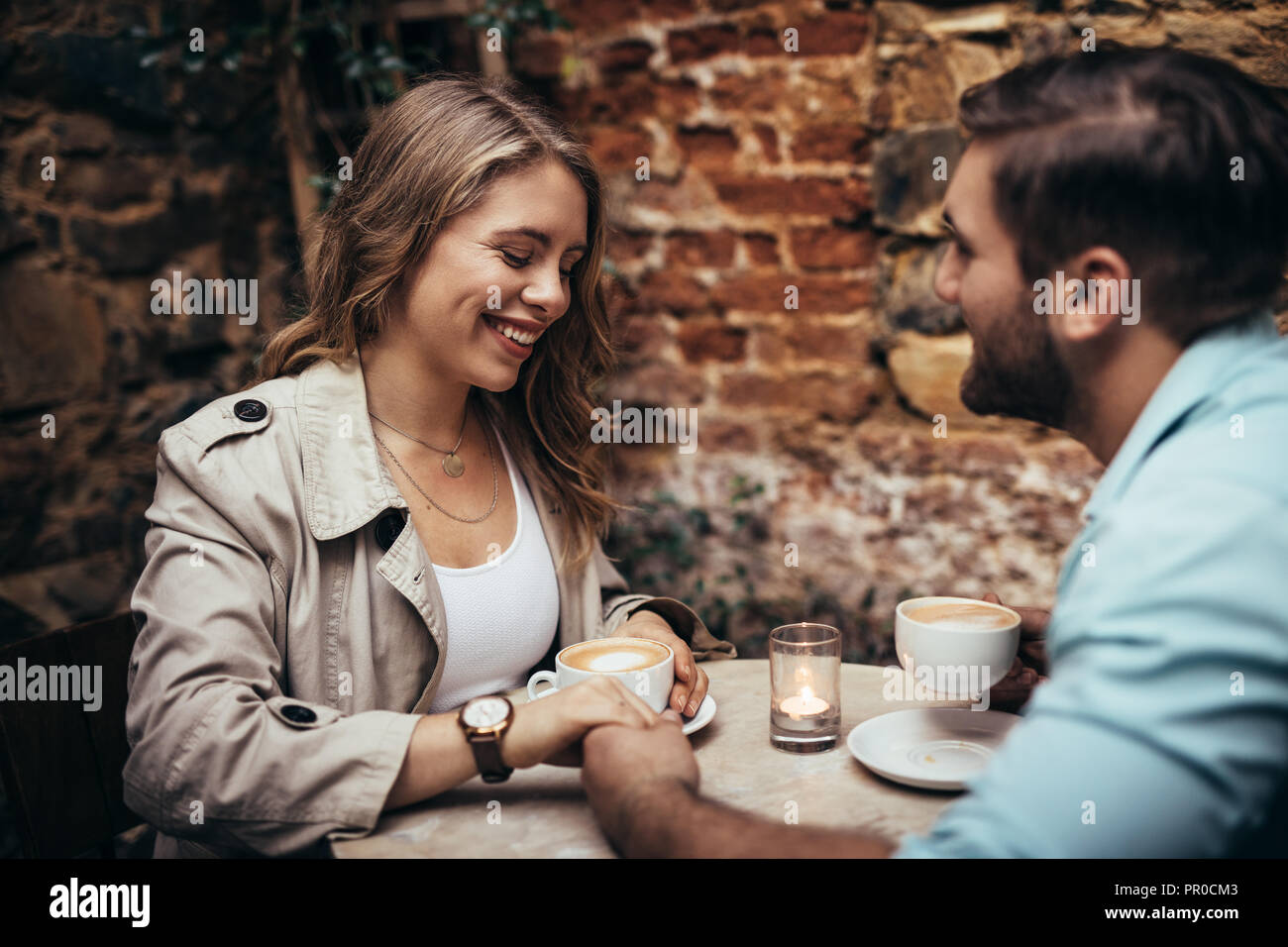 Mann hält die Hand seiner Freundin in einem Restaurant sitzen. Verliebtes Paar im Coffeeshop, Hände halten beim Trinken von Kaffee sitzen. Stockfoto