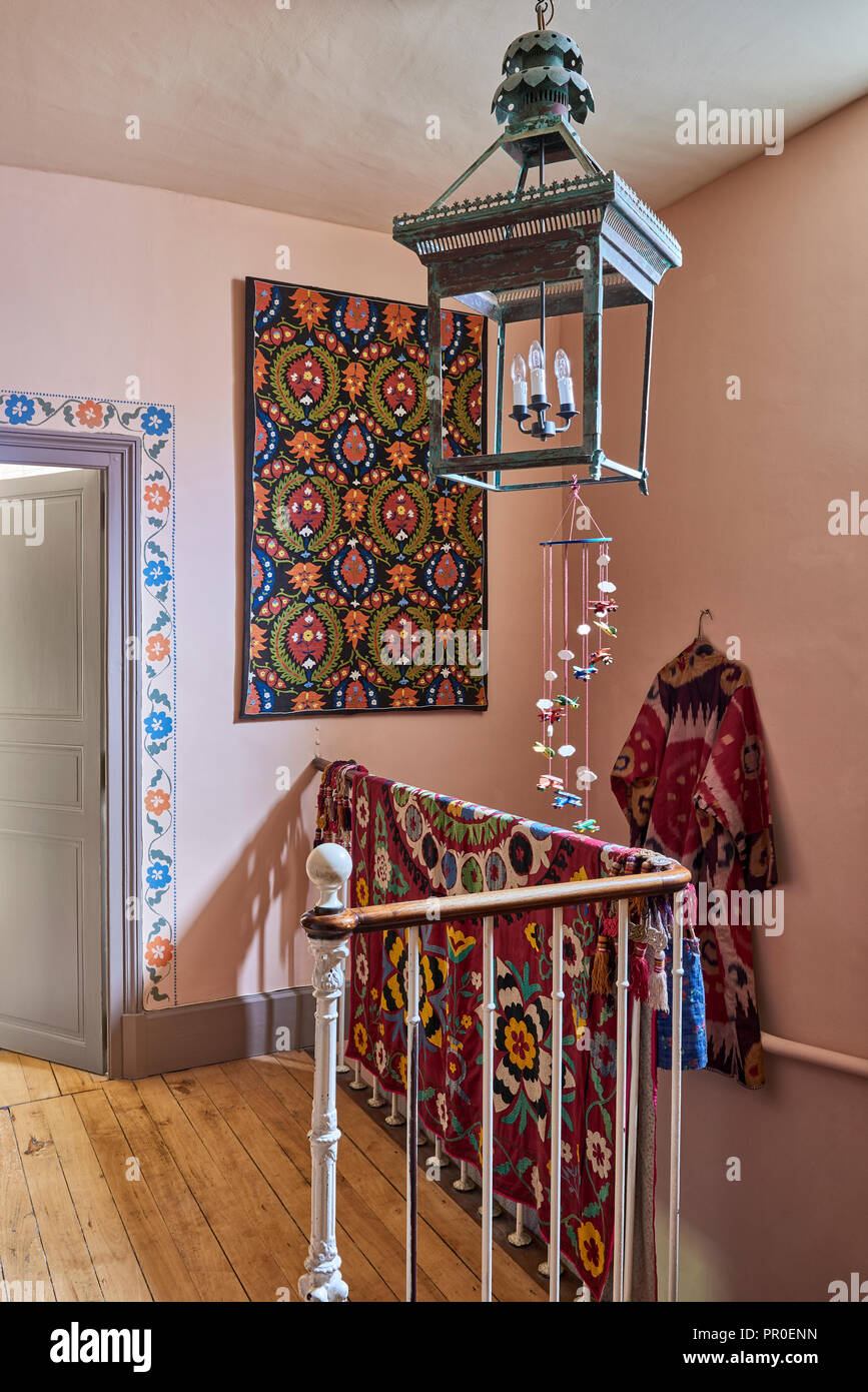Vintage Laterne hängt über Textilwaren auf Geländer mit bunten Wandmalereien Stockfoto