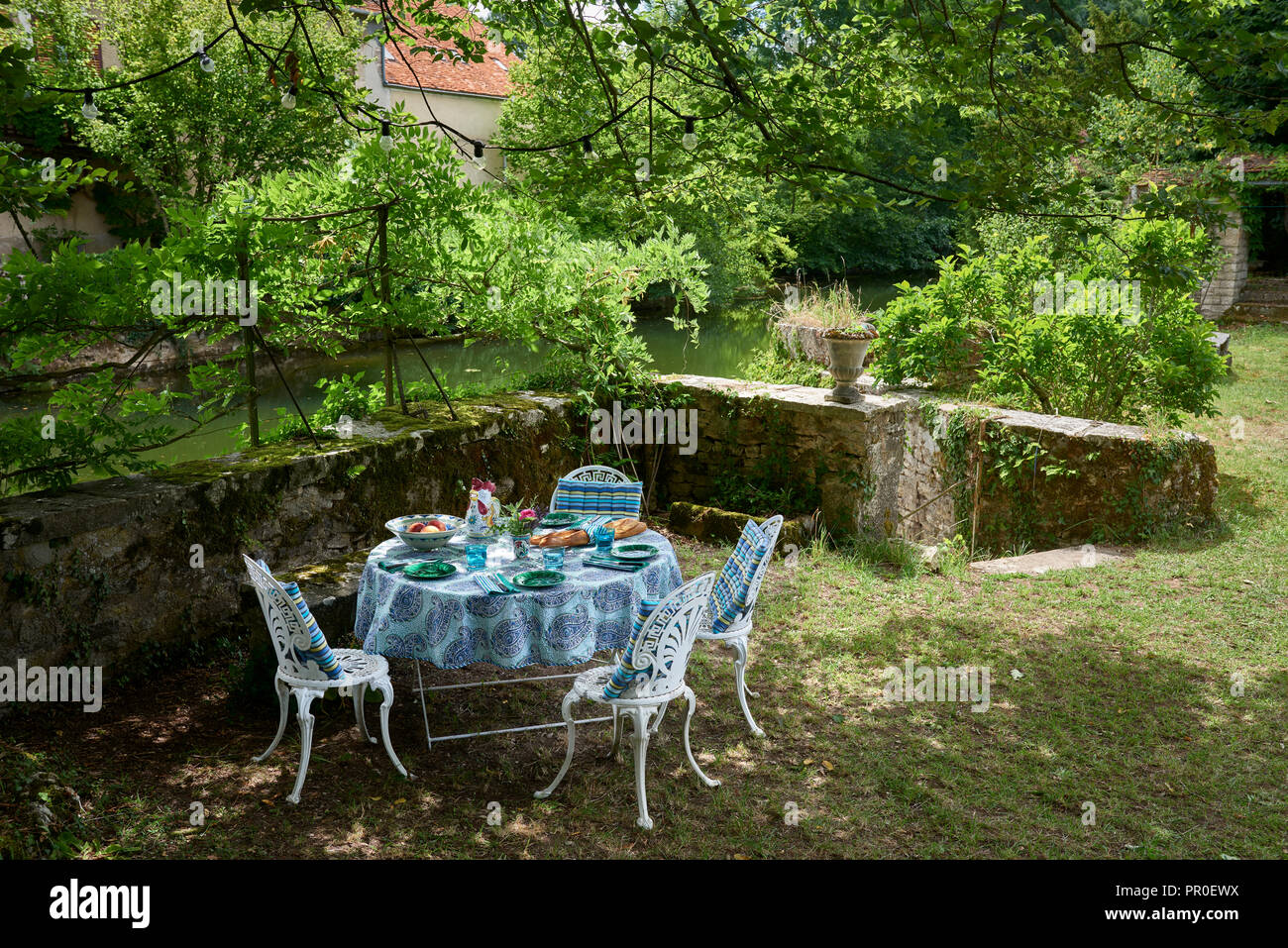 Runder Tisch und Stühle im Garten am Ufer Stockfoto