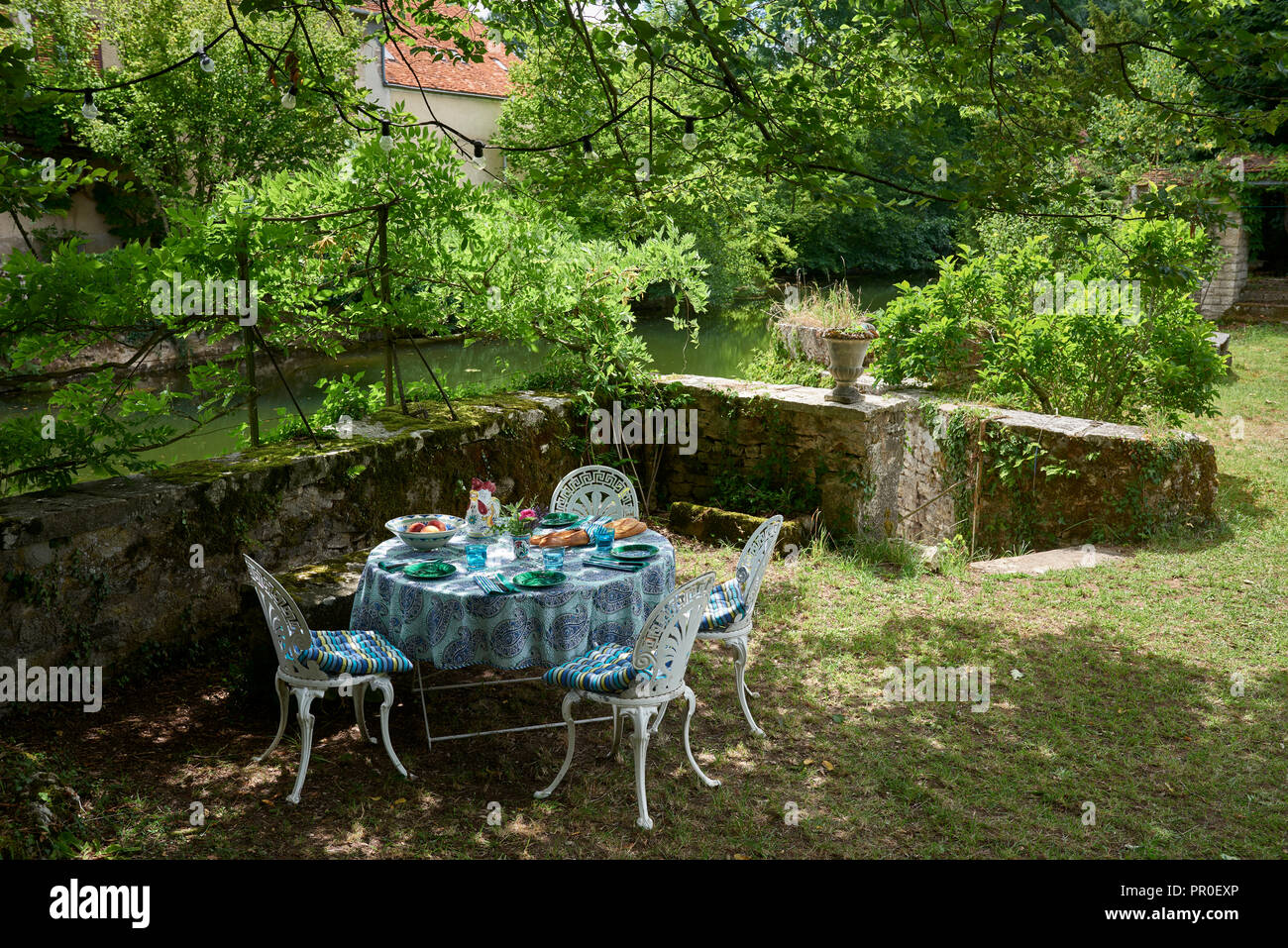 Runder Tisch und Stühle im Garten am Ufer Stockfoto